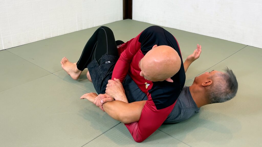 Secure the figure 4 Kimura grip on his left arm.